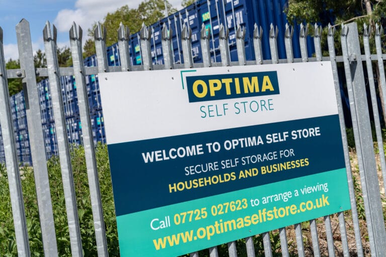 Optima Self Store welcome sign displayed on the perimeter fence at the Corby self storage facility.
